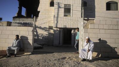 Palestinians sit outside the family home of an alleged abductor after Israeli troops set off an explosion on the top floor in the West Bank City of Hebron July 1, 2014. Ammar Awad/Reuters