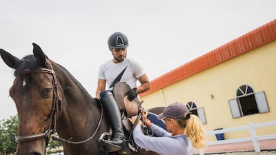 Majid Al Qassimi mounts his horse Celtion at Sharjah Equestrian & Racing Club, with the help of his trainer, Pia Kjellstrom. Alex Atack for The National