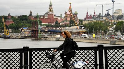This file photo taken on June 6, 2017 shows a woman riding a bicycle along a bridge over the Moskva river with the construction site of the new Zaryadye park seen in the background in central Moscow. AFP / Kirill Kudryavtsev