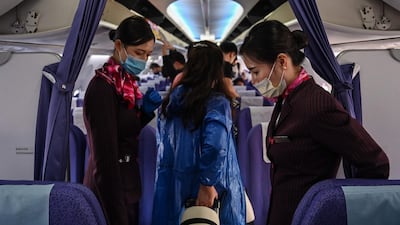 Cabin crew with protective masks welcome passengers on board a flight in Bangkok. AFP