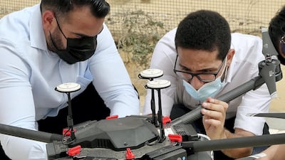 A team of engineers led by Ahmed Borik (right) load up one of the drones being used by Cafu to plant one million ghaf tree seeds in the desert over the next two years. Pawan Singh / The National