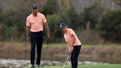 Charlie Woods plays a shot on the ninth hole as Tiger Woods looks on. AFP