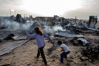 Palestinians inspect the damage caused by an Israeli strike on a camp for the displaced in Rafah. EPA