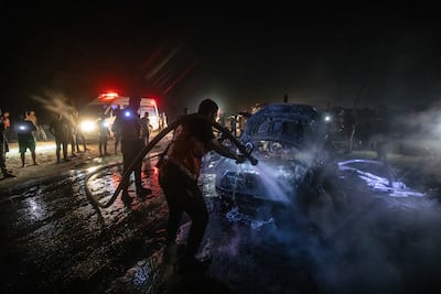 Palestinian civil defence personnel extinguish a fire after an Israeli air strike destroyed a car in Gaza city. EPA