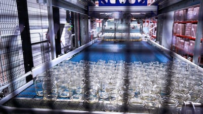 Sterilised glass containers on the automated conveyor system are UV checked before being filled with cheese in the production line. Victor Besa / The National