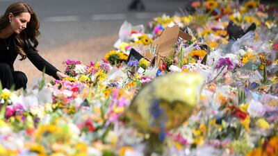 The Princess of Wales looks at floral tributes. AFP