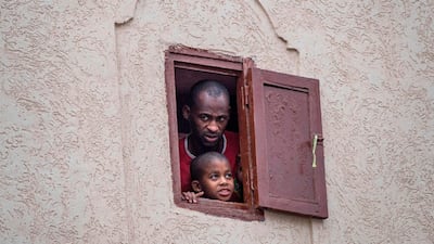 Moroccans confined at home watch from their window as health ministry workers disinfect a road in the capital Rabat. AFP