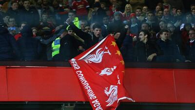 A Liverpool fan holds a flag as he stands amongst Manchester United supporters after their Europa League last-16, second-leg match at Old Trafford on Thursday. Clive Brunskill / Getty Images