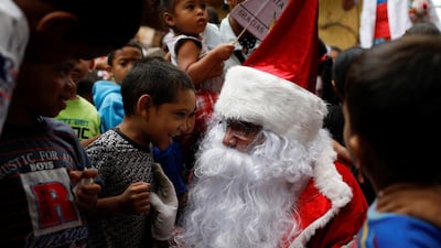 Richard Gamboa, dressed up as Santa Claus, talks with a boy during the 'Santa en las calles' (Santa in the streets) event donating toys, food, and clothes at the slum Cota 905 in Caracas, Venezuela. Reuters