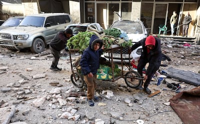 Two men and a boy push a cart carrying vegetables through the rubble after an Israeli strike on Saturday in Gaza City. Reuters