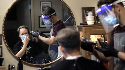 Vin Norton gets a haircut by barber Cristian Lopez at Barber Walter's barbershop, as they both wear masks out of concern for the coronavirus. AP