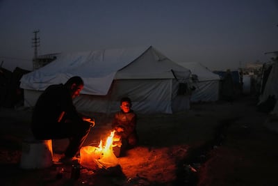Displaced by the war in Gaza, Palestinians seek warmth by the fireside at a camp in the enclave. AP