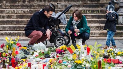 A family lights a candle at floral tributes at a memorial site at the Place de la Bourse in Brussels. The death toll from the bombings in the Belgian capital has risen to 35. Geert Vanden Wijngaert / AP Photo