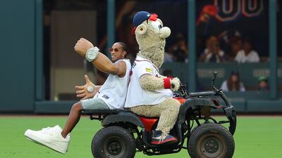 Rapper Ludacris rides on the back of Blooper's ATV to throw out the first pitch before the game between the Atlanta Braves and the Colorado Rockies at Truist Park in Atlanta, Georgia. AFP