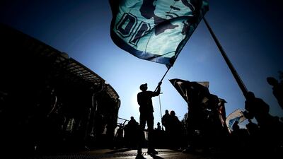 A man waves a flag at the effigy of late Argentinian football legend Diego Maradona, as people gather outside the San Paolo stadium in Naples to mourn the death of Maradona. AFP
