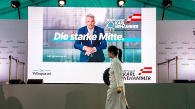 A person walks by a poster of Austrian Chancellor Karl Nehammer at the OVP Austrian People's Party headquarters in Vienna. AP