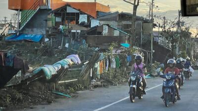 Motorcyclists move past damaged houses in Cebu. EPA