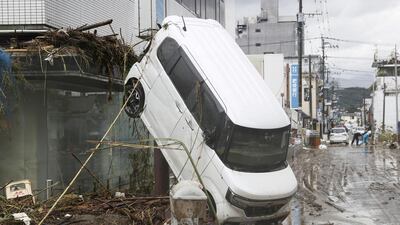 A car is left with its back wheels in the air after being swept up in heavy flooding in the southern Japanese town of Hitoyoshi, Kumamoto prefecture. Reuters