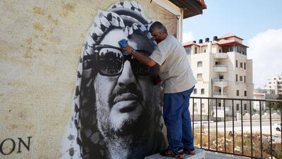 A Palestinian man cleans a portrait of late Palestinian leader Yasser Arafat in Ramallah. Abbas Momani / AFP Photo