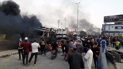 Iraqi protesters gather as smoke rises from a burning military truck after clashes between protesters and Iraqi policemen in Nasiriyah city, some 370km southeast of Baghdad, Iraq. EPA