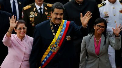 Venezuela's President Nicolas Maduro, center, with his wife Cilia Flores, left, and constitutional assembly president Delcy Rodriguez wave as they arrive to the national assembly building for a session of the constitutional assembly in Caracas, Venezuela