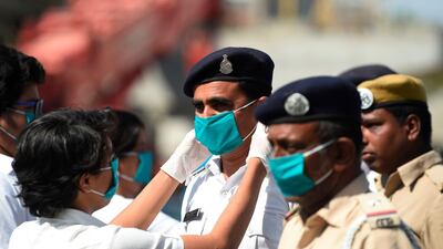 A student adjusts a free facemask to a policeman during a facemaks donation campaing in Ahmedabad. AFP
