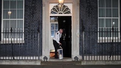 In a more peaceful scene in Downing St, a doorman lays a candle lit by Prime Minister Boris Johnson as a tribute to Sarah Everard. Reuters