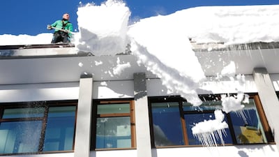A worker removes snow from the roof of a building in Davos, Switzerland on Tuesday. REUTERS