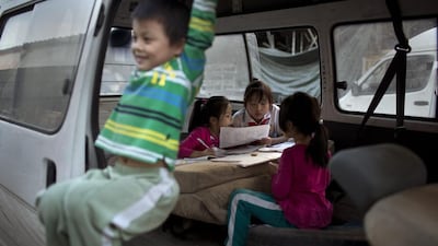 Chinese girls do their homework inside a delivery van while a boy enjoys swinging from the van's door at a second-hand furniture market in Beijing, China. Alexander F Yuan / AP Photo