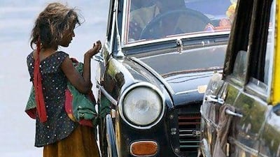 A young Indian girl with a baby begs for coins from a taxi at a traffic intersection in Bombay. AFP