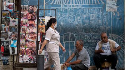 A maid from the Philippines wears a mask to help stop the spread of the new coronavirus as she walks in front of a newspaper kiosk in central Beirut's commercial Hamra Street, in Beirut, Lebanon. AP Photo