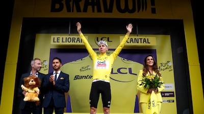 UAE Team Emirates' Tadej Pogacar celebrates on the podium wearing the overall leader's yellow jersey. Reuters