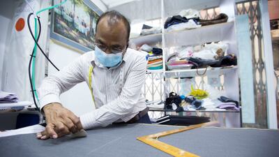 A tailor prepares a piece of cloth at Meena Bazaar.