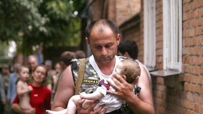 A Russian police officer carries a released baby from a school seized by heavily armed masked men and women in the town of Beslan in the province of North Ossetia near Chechnya, on September 2, 2004. Viktor Korotayev / Reuters