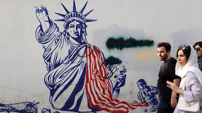 People walk in front of an anti-US mural next to the former US embassy in Tehran, Iran. EPA