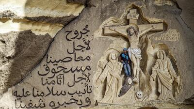 Polish artist Mario, sculptor of St. Simon the Tanner Monastery complex, poses for a picture alongside a scene relief depicting the Crucifixion of Jesus Christ and a verse in Arabic from the Biblical Book of Isaiah reading "he was wounded for our transgressions, he was bruised for our iniquities, the chastisement of our peace was upon him; and with his stripes we are healed", at the church in the Egyptian capital Cairo's eastern hillside Mokattam district, . Mario spent more than two decades carving the rugged insides of the seven cave churches and chapels of the rock-hewn St. Simon Monastery and church complex atop Cairo's Mokattam hills, with designs inspired by biblical stories. It was all done to fulfil the wishes of the church's parish priest who met Mario in the early 1990s in Cairo. The Polish artist, who had arrived in Egypt earlier on an educational mission, was then looking for an opportunity to serve God at the monastery. AFP