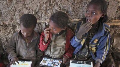 Children play with tablet computers given to them by the One Laptop Per Child project in the village of Wenchi, Ethiopia.