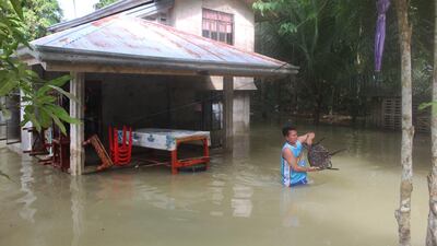 A resident gathers belongings from their flooded house after a tropical depression hit Loboc town on January 2, 2018. Four people were killed early on Tuesday as a tropical storm unleashed heavy rain and triggered deadly landslides. Michael Ligalig / AFP