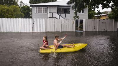 Nosh and Charlotte Talbot paddle down Queens Road during flooding in Rosslea, a suburb of Townsville in Australia's Queensland state, Australia. EPA