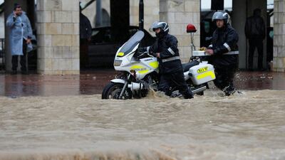 Traffic policemen push a motorcycle through a flooded street in Amman. Reuters