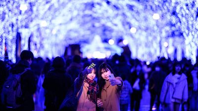 Revellers take pictures among the festive light installations in Tokyo's Shibuya district. AFP