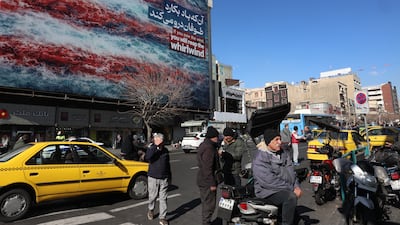 Iranians walk near an anti-US billboard at Enqelab Square in Tehran during anti-government protests. EPA