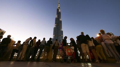 Tourists look at a light show at the Burj Khalifa tower at dusk in Dubai. Visitor numbers have remained healthy this year. Chris Ratcliffe / Bloomberg