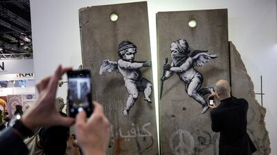 Visitors take photographs of the 'replica separation barrier' created by British street artist Banksy as it stands on display at the Palestine tourist stand at the World Travel Market at the Excel centre in London. Reuters