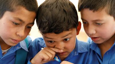 Afghan boys read books inside a mobile library bus.
