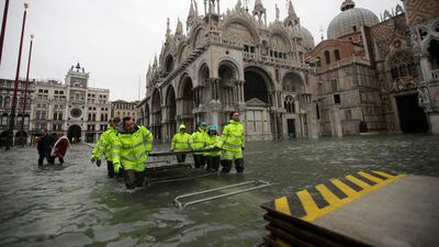 Municipality workers carry wooden boards to create a trestle bridge in a flooded St. Mark's Square at Venice. AP Photo