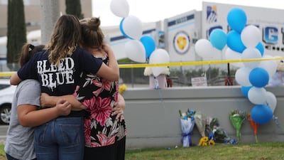 SANTA CLARITA, CALIFORNIA - NOVEMBER 15: A Saugus High School student (2nd L) is embraced as she visits a makeshift memorial in front of the school for victims of the shooting there on November 15, 2019 in Santa Clarita, California. The shooting left two students dead and others wounded while a suspect in the shooting is being treated at a local hospital for a gunshot wound to the head. Mario Tama/Getty Images/AFP == FOR NEWSPAPERS, INTERNET, TELCOS & TELEVISION USE ONLY ==
