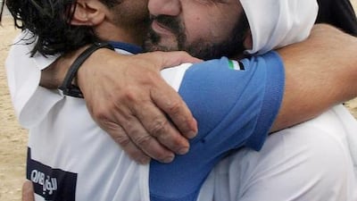 A file picture taken on December 14, 2006 of Vice President and Ruler of Dubai Sheikh Mohammed bin Rashid hugging his son Sheikh Rashid bin Mohammed who finished first in the equestrian endurance competition during the 15th Asian Games in the desert outside Doha. Khaled Nofal / AFP Photo