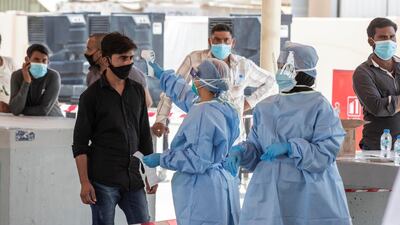 Men have their temperatures taken at a testing centre in Mussaffah. Antonie Robertson / The National