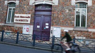 A woman rides her bike next to Elementary School Gambetta, near Paris, during a nationwide strike day. EPA